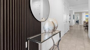 Un couloir moderne avec une console en verre, des vases décoratifs et un grand miroir.