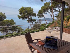 A wooden table with a laptop and a notebook on a balcony overlooking the sea. - Ocean views. A 5-minute walk from the beach. Swimming Pool (Llafranc)