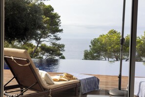 A lounge chair with a book and a straw hat on a wooden deck overlooking a swimming pool and trees. - Ocean views. A 5-minute walk from the beach. Swimming Pool (Llafranc)