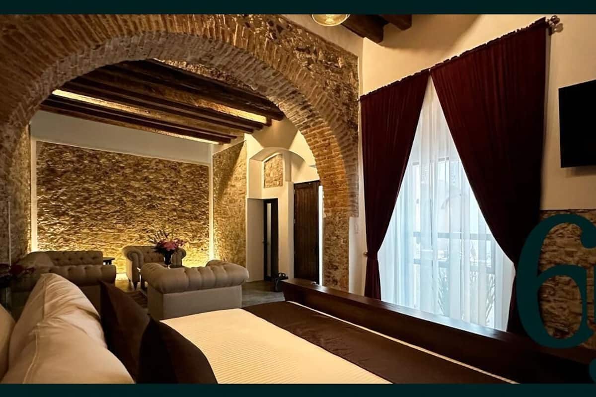 Ein gemütliches Zimmer mit Steinwand, Kamin und großem Fenster mit Vorhängen.