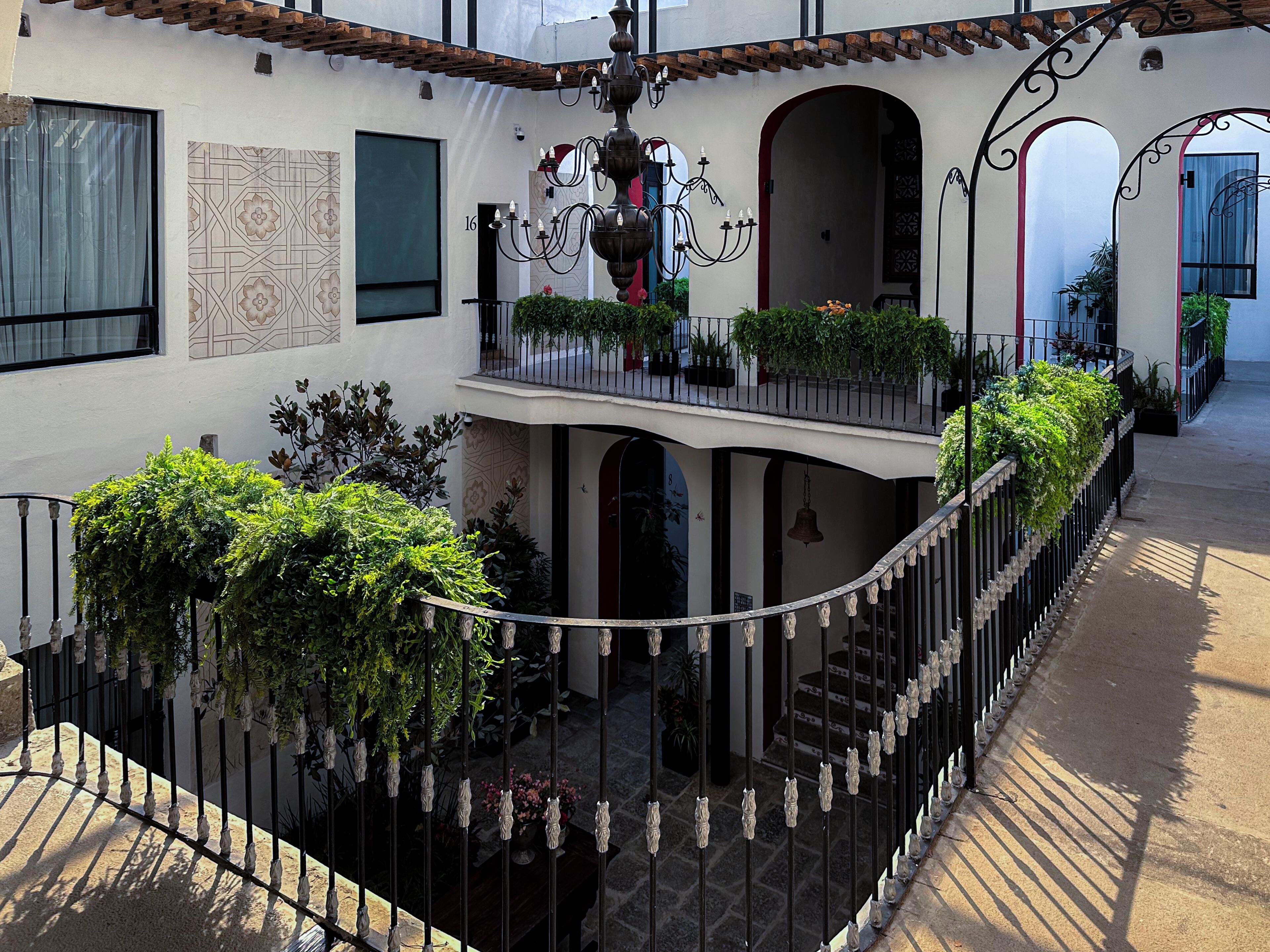 A multi-level courtyard with a wrought iron fence, potted plants, and a decorative chandelier.