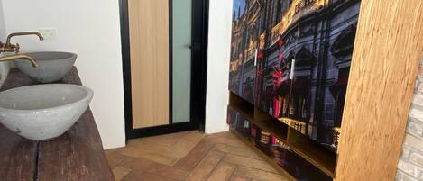 A room with a wooden table, a large painting of a building, a door, and a tiled floor.