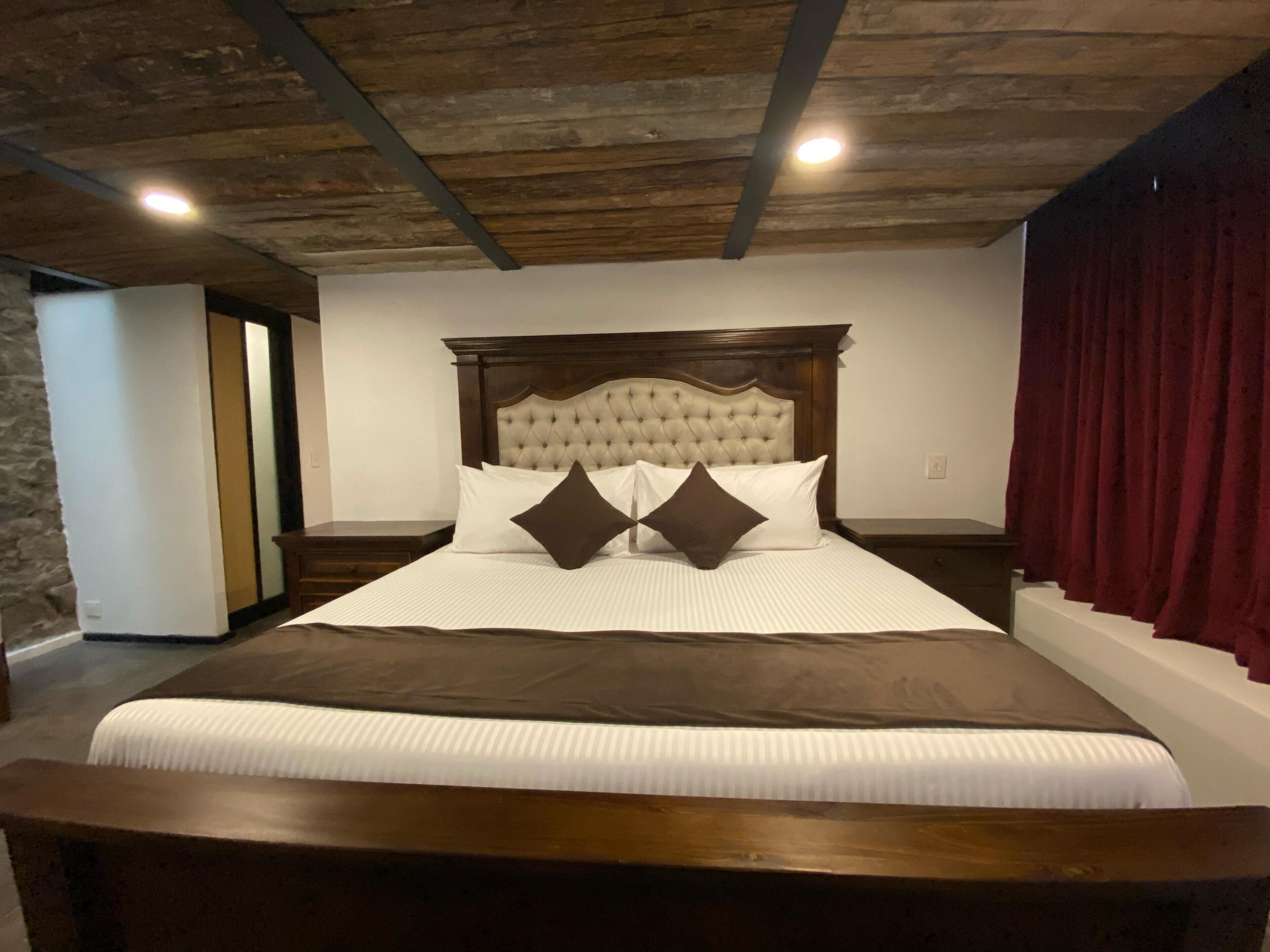 A large bed with a wooden headboard, white bedding, and two dark pillows.