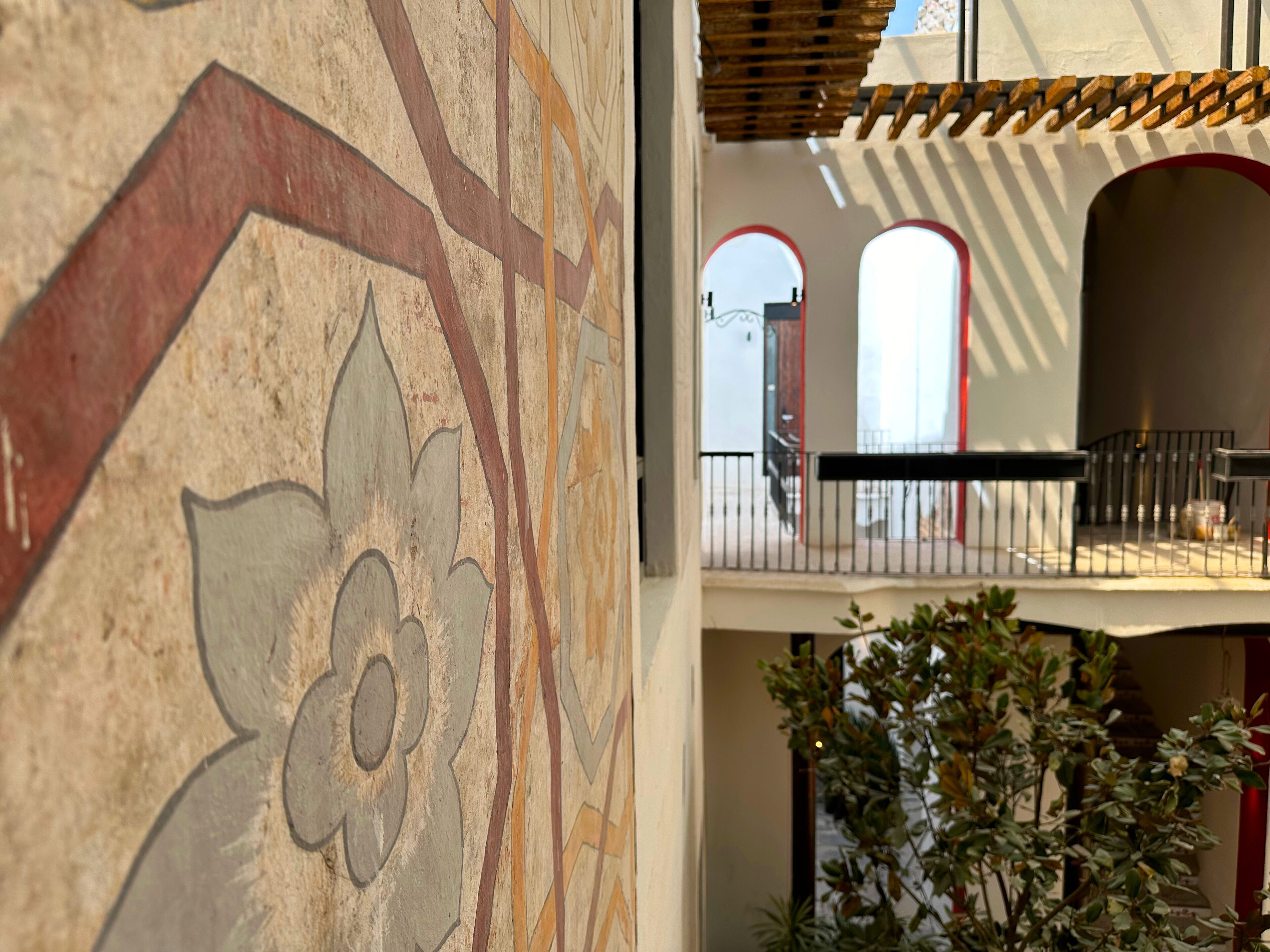 A detailed wall mural with geometric patterns and a balcony with a railing.