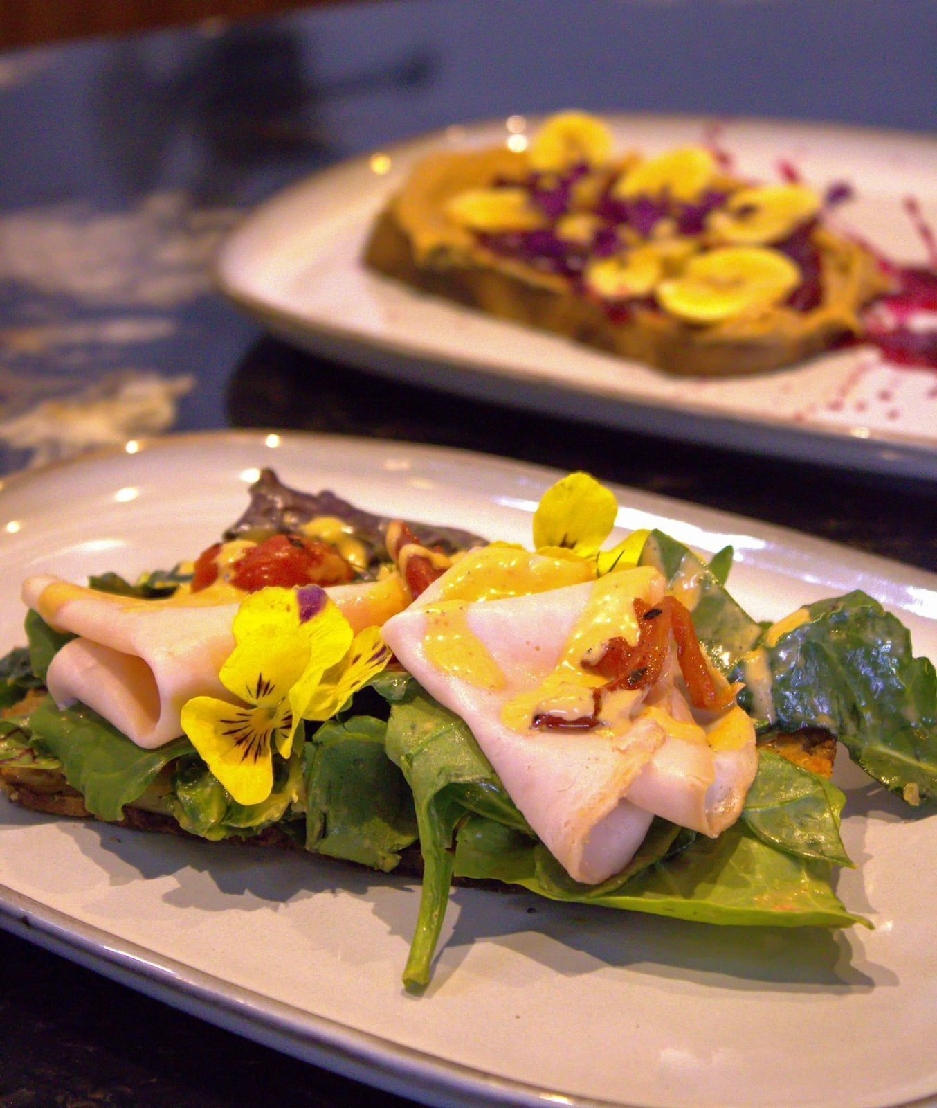 A plate of food with a salad, ham, and yellow flowers.