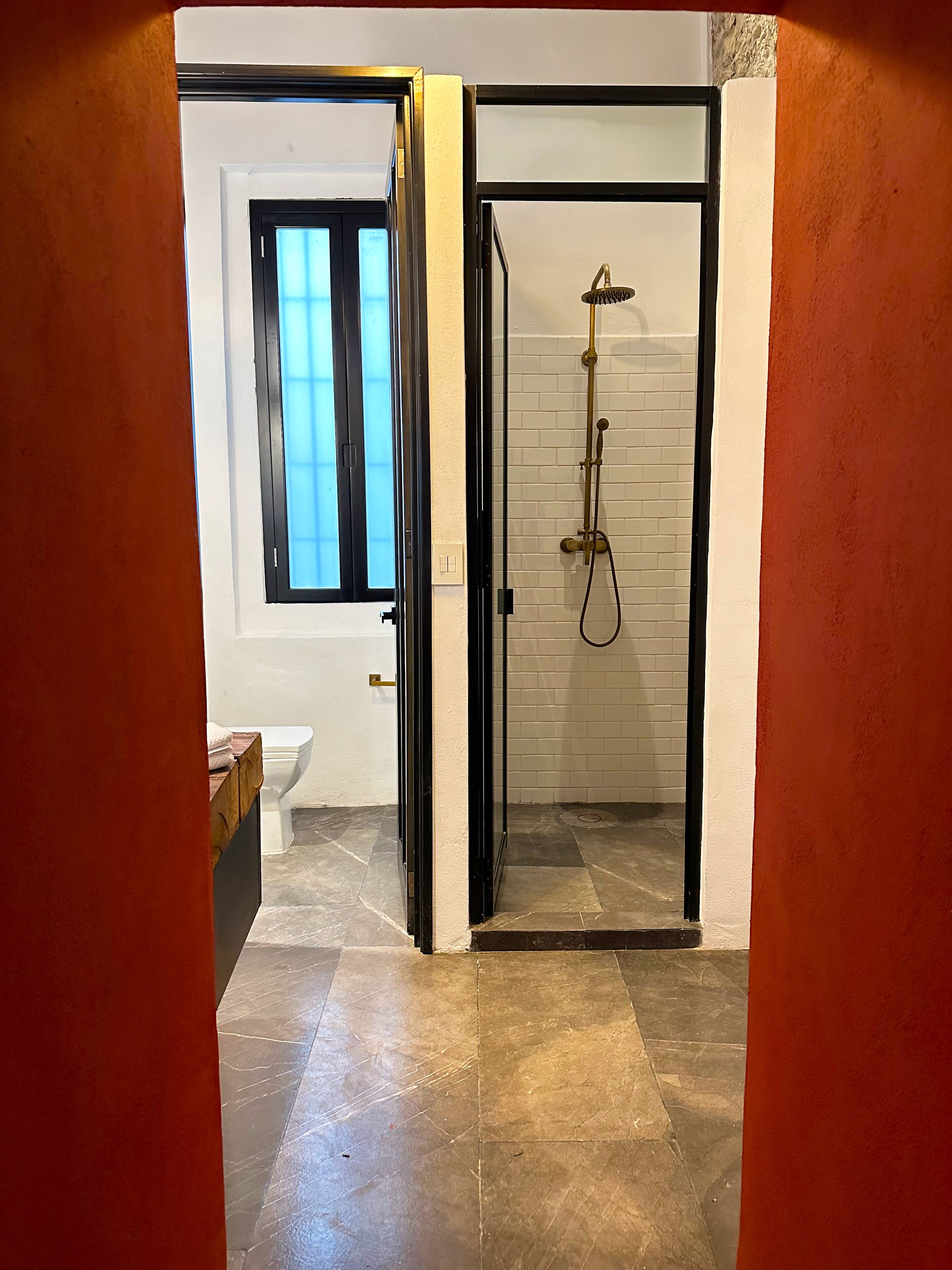 A bathroom with a glass shower enclosure, a toilet, and a sink.