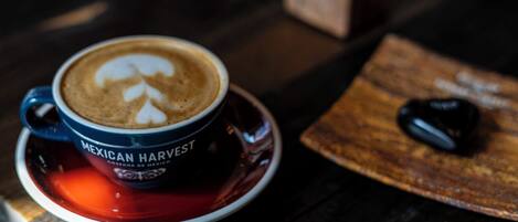 A cup of coffee with latte art labeled 'Mexican Harvest' on a saucer.