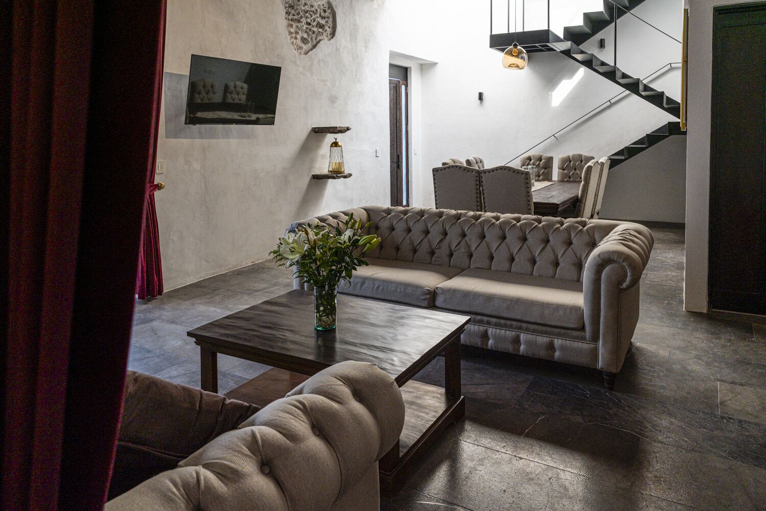 A living room with a sectional sofa, a coffee table, and a staircase in the background.