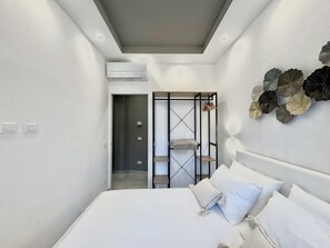 Ein modernes Schlafzimmer mit Bett, begehbarem Kleiderschrank und Deckenleuchte.