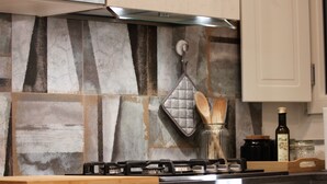 A kitchen with a gas stove, wooden countertop, and a backsplash with a geometric pattern. - Ponte Vecchio｜Tower of Gelfi (Firenze)
