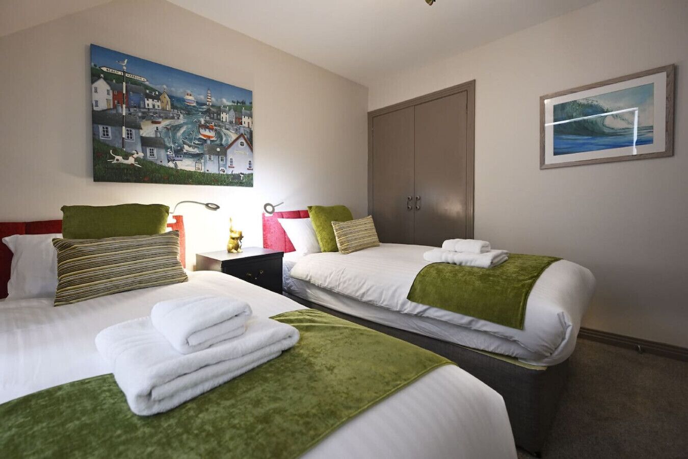 Una camera d'albergo con due letti, un comodino, un armadio e due quadri.