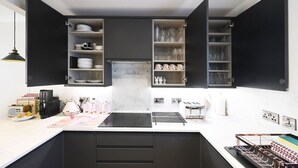 Una cocina moderna con armarios abiertos, una isla central y diversos electrodomésticos.