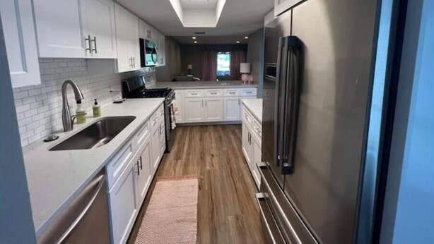 Una cucina moderna con mobili bianchi, un frigorifero in acciaio inossidabile e un lucernario.