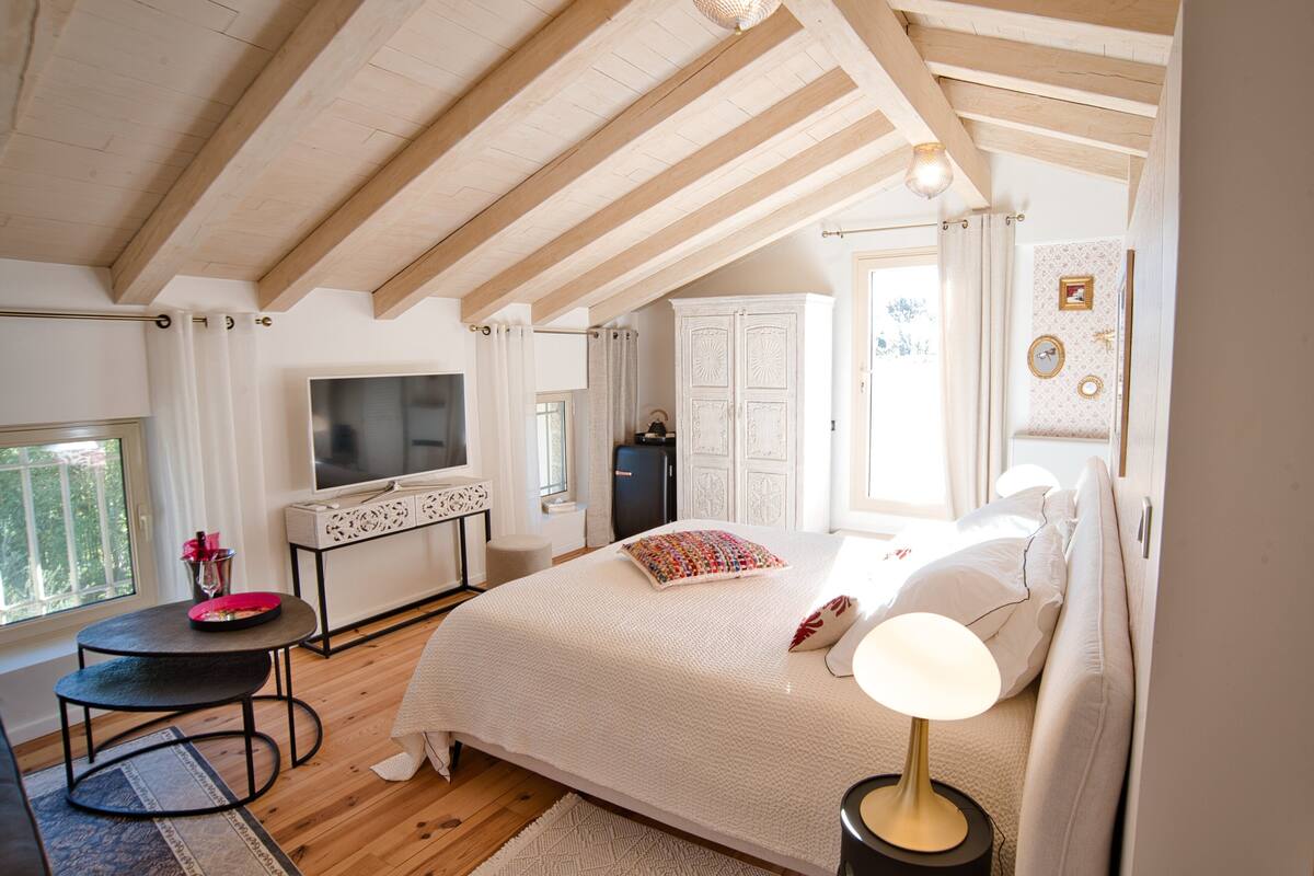 Quarto com cama, TV, escrivaninha e janela.