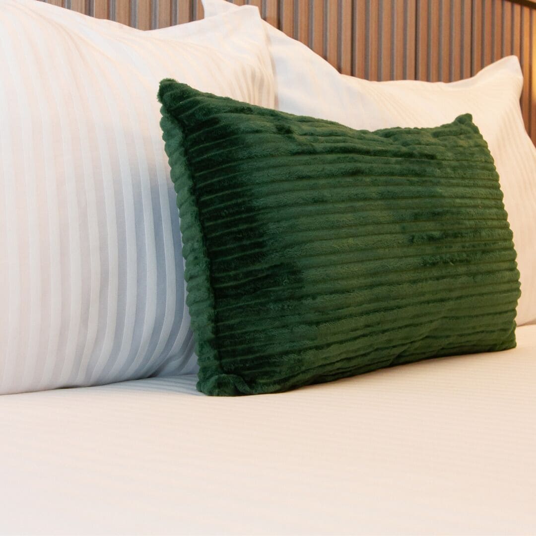 A bed with white pillows and a green pillow.