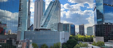 A modern cityscape with high-rise buildings, including a distinctive triangular skyscraper and a building with 'sura' signage.