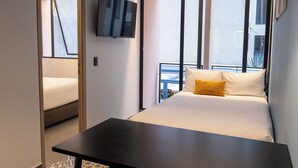 Et moderne hotelværelse med en seng, et fladskærms-TV, en balkon med gelænder og et stort vindue.