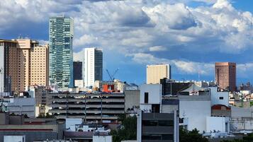 Un paisaje urbano con varios edificios altos, incluyendo un rascacielos destacado de diseño singular.