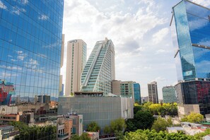A cityscape with modern high-rise buildings, including a distinctive triangular skyscraper and a building with a grid-like facade. - NIU Reforma (Mexico City)