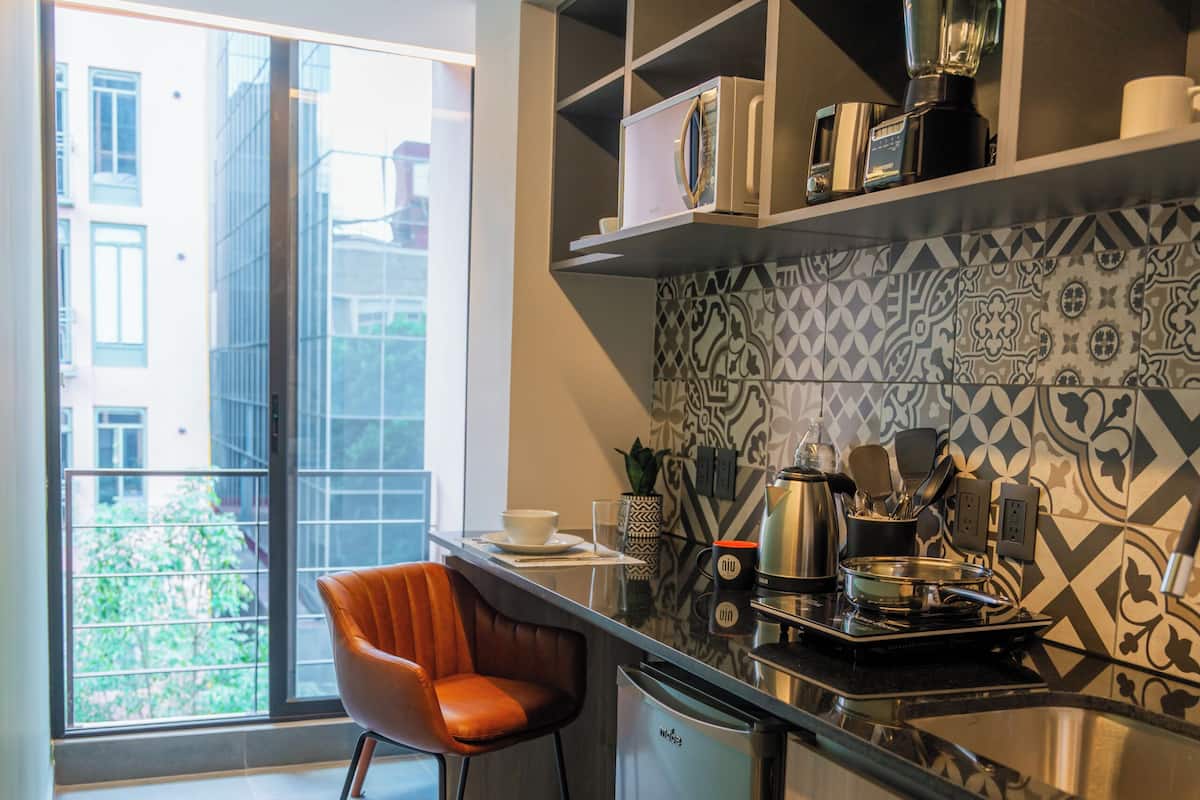 Una cocina moderna con horno empotrado, cafetera y licuadora sobre la encimera.