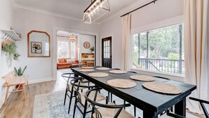 Un espace repas avec une longue table, des chaises noires et des sets de table en fibres tressées.
