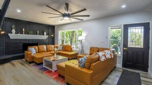 Un salon moderne avec une cheminée, des canapés en cuir, une table basse et un ventilateur de plafond.