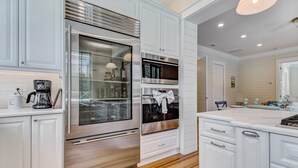 Una cucina moderna con mobili bianchi, elettrodomestici in acciaio inossidabile e pavimento in legno.