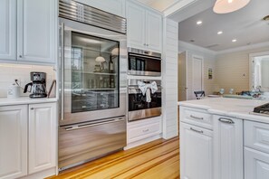 A modern kitchen with white cabinetry, stainless steel appliances, and a wooden floor. - Old Town Casita 3BR/3BA 10 minutes to downtown and the beach with Golf Cart (Fernandina Beach)