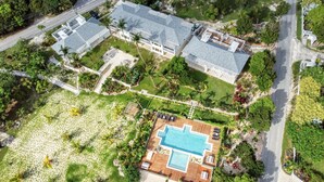 Oversigtsbillede af et resort med en stor swimmingpool, flere gæstevillaer og frodig beplantning.