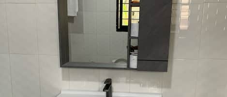 Un baño con un lavamanos blanco, un espejo y un armario con dos puertas.