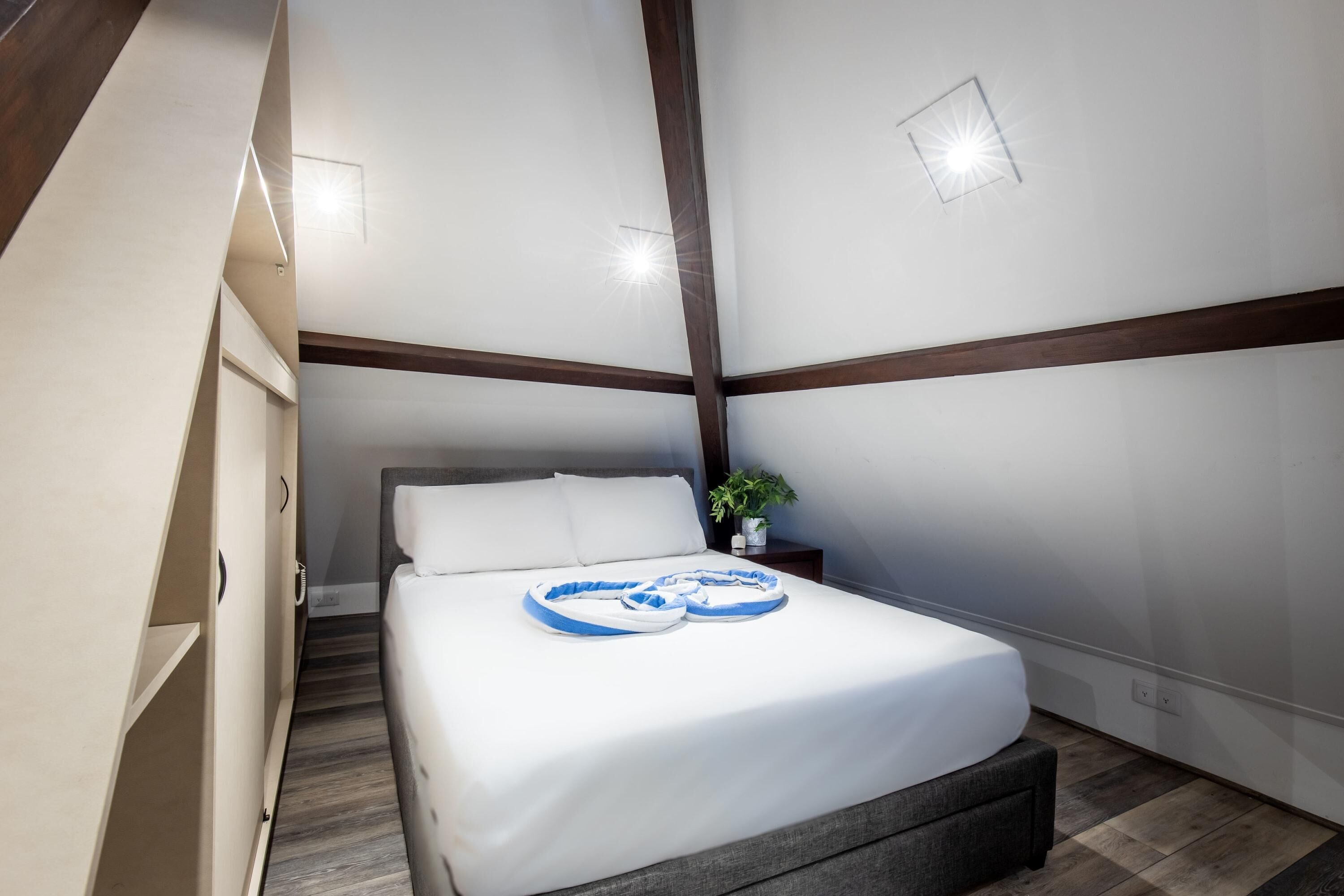 Un dormitorio moderno con cama, mesita de noche y una planta en maceta.