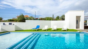 A swimming pool with clear blue water, surrounded by white walls and a small white building. - Genesis Apartments in Jan Thiel - Swimming Pool (Willemstad)