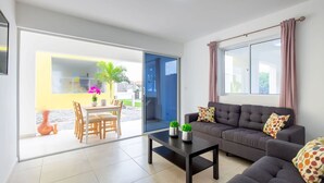 A modern living room with a sofa, coffee table, and a dining area with chairs and a table. - Genesis Apartments in Jan Thiel - Swimming Pool (Willemstad)
