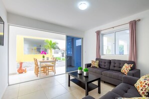 Ein modernes Wohnzimmer mit Sofa, Couchtisch und Essbereich mit Stühlen und Tisch.