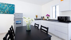 A modern kitchen with white cabinets, a black countertop, and a dining area with a black table and chairs. - Genesis Apartments in Jan Thiel - Swimming Pool (Willemstad)