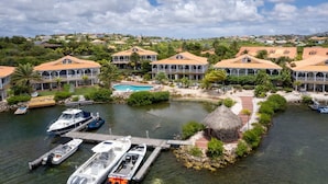 Ein Küstenresort mit mehreren Villen, einem Swimmingpool und Booten, die am Steg vor Anker liegen.