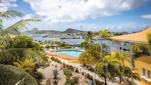 Ein Resort mit Pool, Palmen und Booten im Hintergrund.