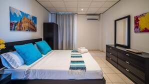 A hotel room with a bed, a dresser, a mirror, and artwork on the walls. - Stunning Balcony View Spacious 2BR Apt at Unique Location (Willemstad)