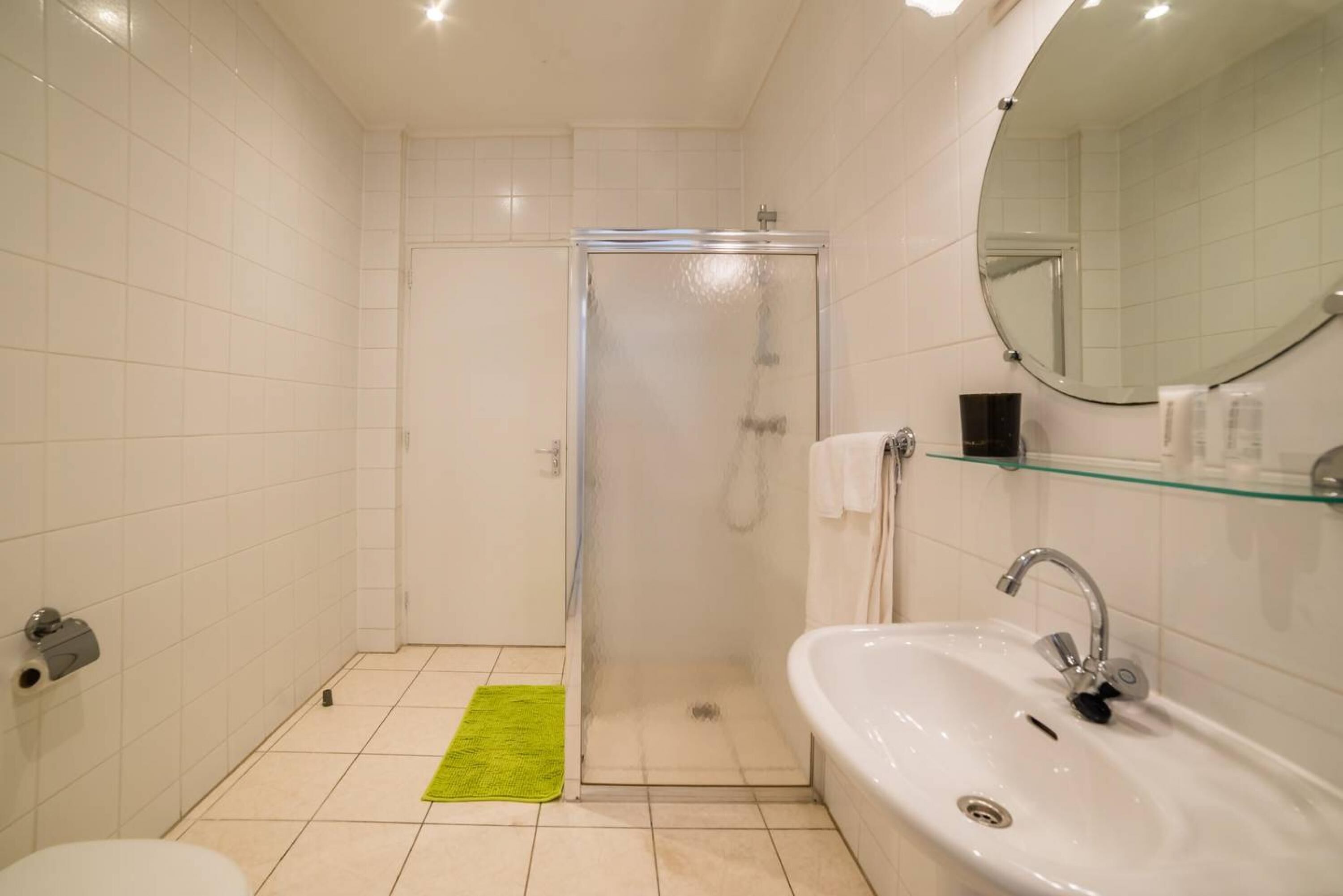 Een badkamer met een douche, toilet, wastafel en een spiegel.