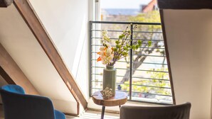 Ein Zimmer mit Oberlicht, einem kleinen Tisch mit Blumen in einer Vase und Blick ins Freie.