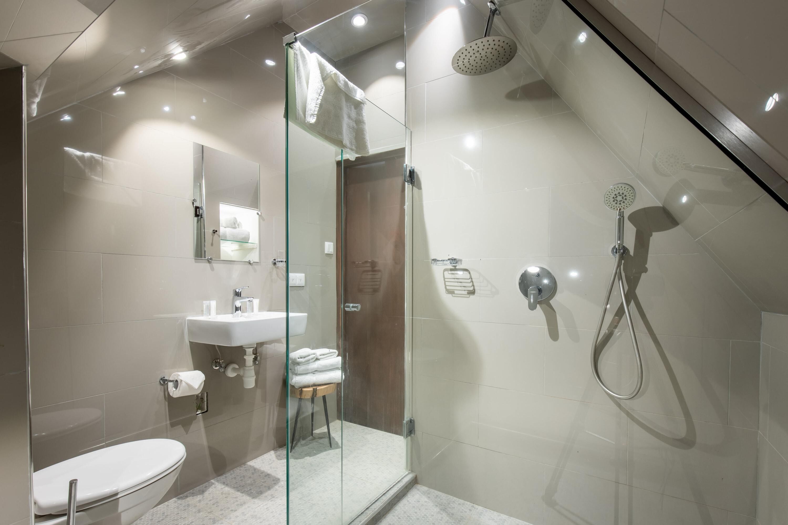 A modern bathroom with a glass-enclosed shower, a toilet, and a sink.
