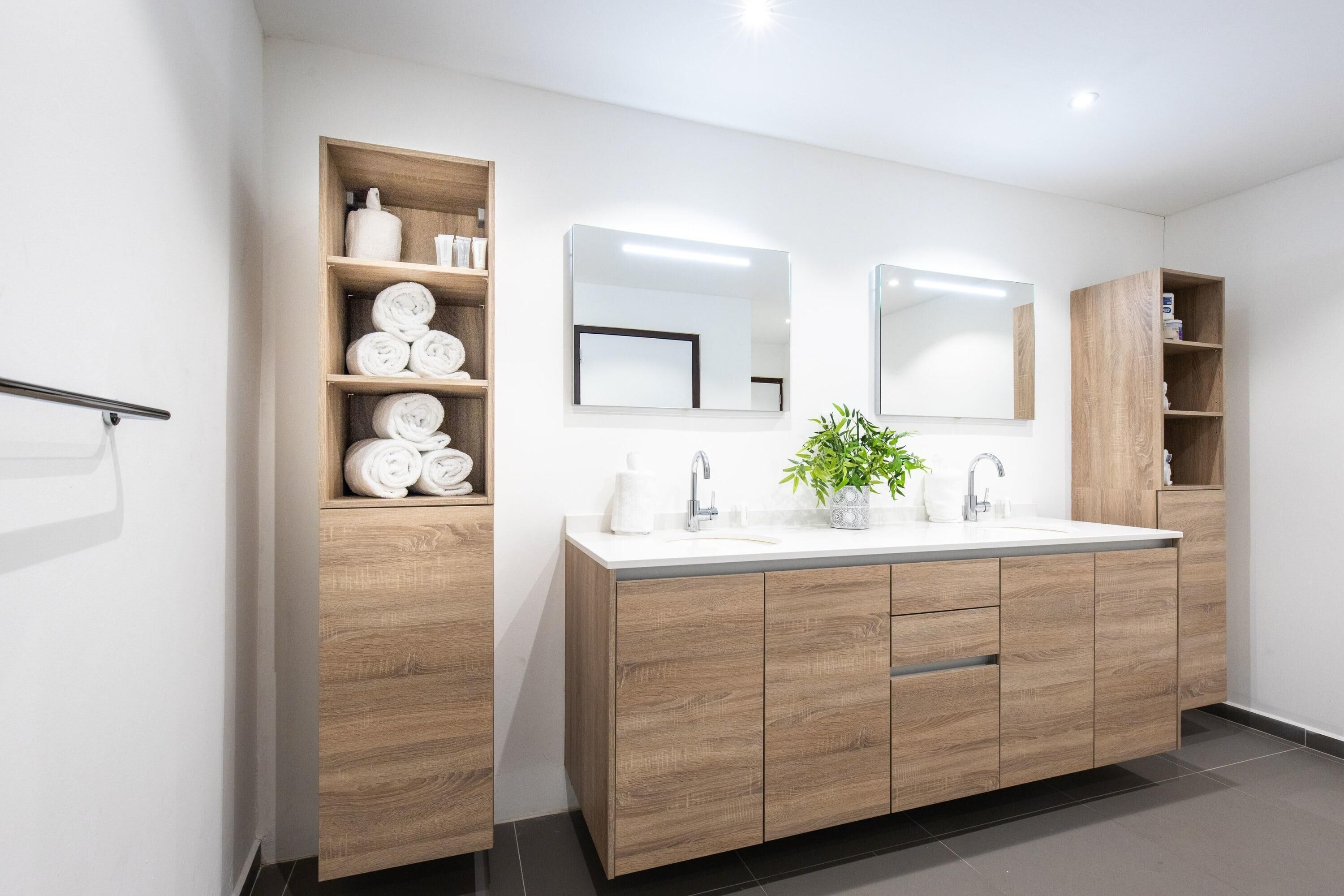 Un baño moderno con tocador de madera, un espejo grande y estantes empotrados.
