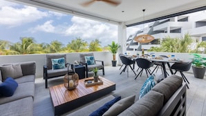 A modern outdoor living area with a sofa, dining table, and chairs. - Blue Bay The Reef Balcony (Sint Michiel)