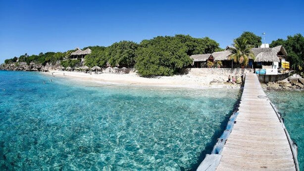 A wooden pier leading to a beach with overwater bungalows and clear turquoise water. - Cliff Villa - Award Winning Luxury Retreat (Sabana Westpunt)