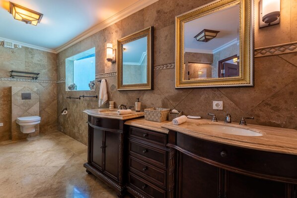 A bathroom with two sinks, dark wooden cabinets, marble flooring, and wall-mounted mirrors. - Cliff Villa - Award Winning Luxury Retreat (Sabana Westpunt)