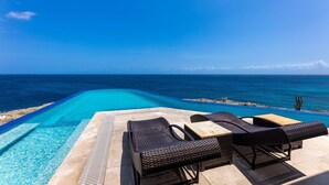 A poolside area with lounge chairs and a view of the ocean. - Cliff Villa - Award Winning Luxury Retreat (Sabana Westpunt)