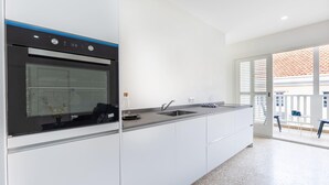 Una cuina moderna amb forn integrat, un rentapeus i una finestra amb vista a un balcó.