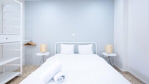 Habitació d'hotel moderna amb llit, un armari i dues taules de nit amb làmpades.