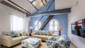 A living room with a sofa, armchair, ottoman, and a staircase. - NEW The Yellow House - Renovated Monumental Penthouse (Willemstad)
