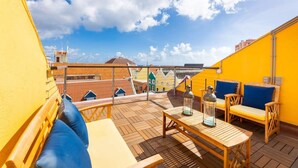A rooftop terrace with wooden furniture, a table, and a lantern. - NEW The Yellow House - Renovated Monumental Penthouse (Willemstad)